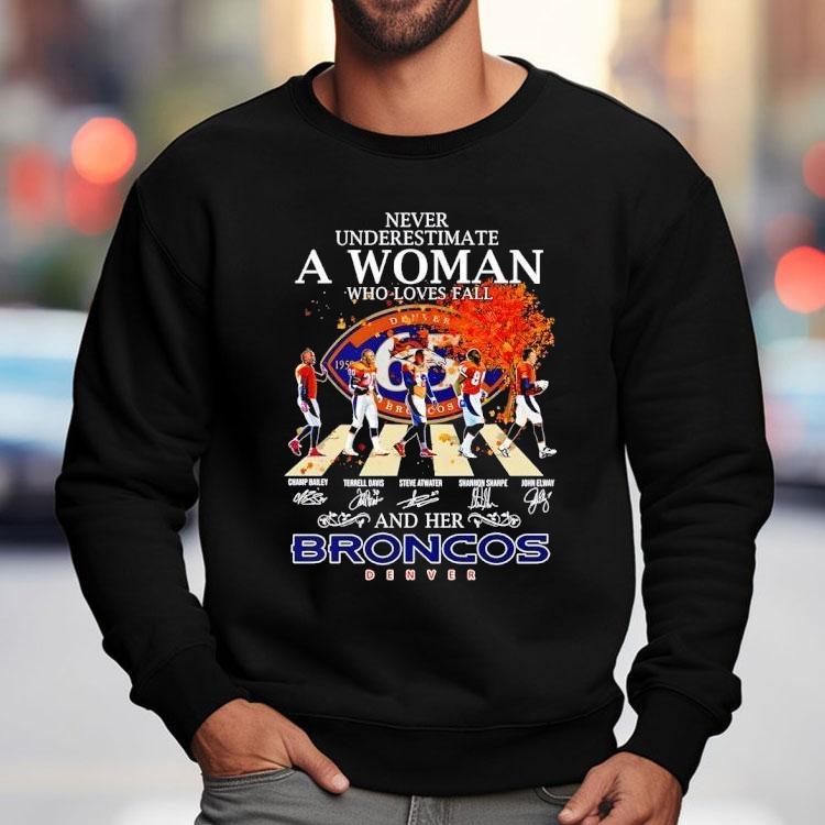 Never Underestimate A Woman Who Loves Fall And Her Denver Broncos Walking Across Signatures Shirt