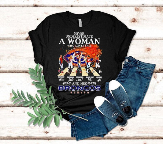 Never Underestimate A Woman Who Loves Fall And Her Denver Broncos Walking Across Signatures Shirt